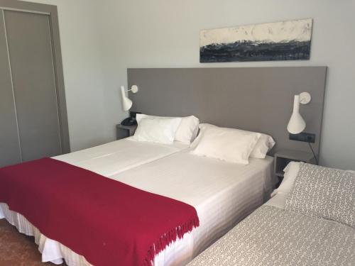 two beds in a bedroom with a red blanket at Hotel Valjunco in Valencia de Don Juan