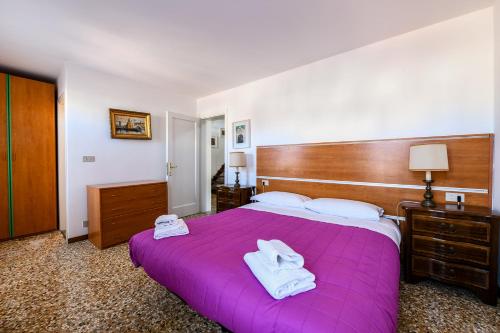 1 dormitorio con 1 cama morada y 2 toallas en Rialto Apartment en Venecia