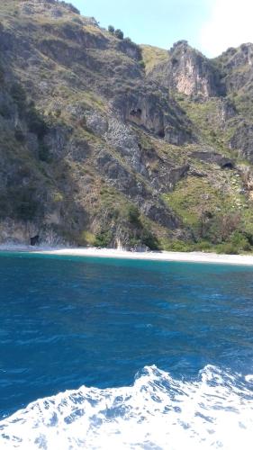 a beach with blue water and a mountain at Tenuta del Bifan in Policastro Bussentino