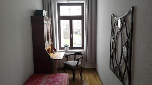 um quarto com uma secretária, uma janela e uma cadeira em Bastians Herberge em Leipzig