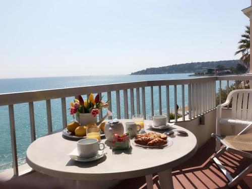 einen Tisch mit Essen auf einem Balkon mit Meerblick in der Unterkunft Hôtel Le Dauphin in Menton