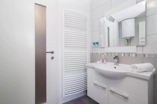 a white bathroom with a sink and a mirror at Charming Apartment in Koper