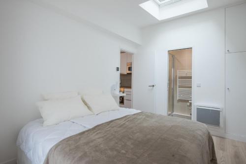 une chambre blanche avec un lit et une fenêtre dans l'établissement Vintage, F3 avec terrasse, Villa Saint Charles, à Paris