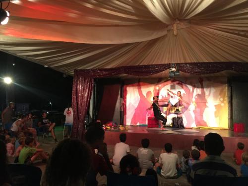 a group of people watching a band on a stage at hu I Pini village in Fiano Romano