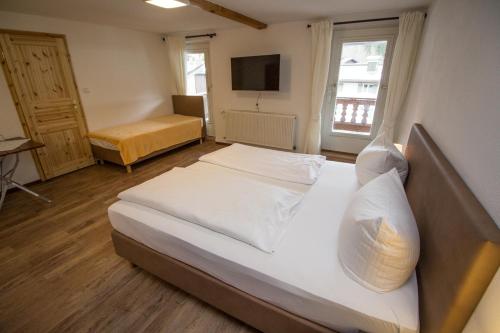 1 dormitorio con 2 camas y TV. en Pension Oberwirt, en Fischbachau