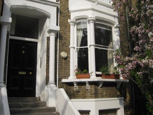 una casa con una puerta negra y una ventana en Olympia W14 Two-Bedroom Apartment en Londres