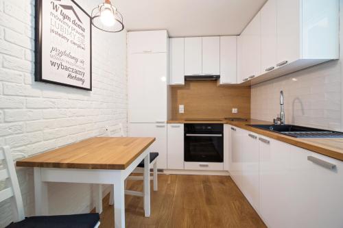 uma cozinha com armários brancos e uma mesa de madeira em Ostoja em Rzyki
