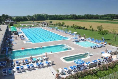 a large swimming pool with chairs and umbrellas at Guest Accomodation Škerlak in Moravske-Toplice