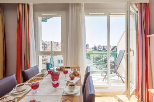 a dining room with a table and a balcony at Résidence Pierre & Vacances Premium Haguna in Biarritz