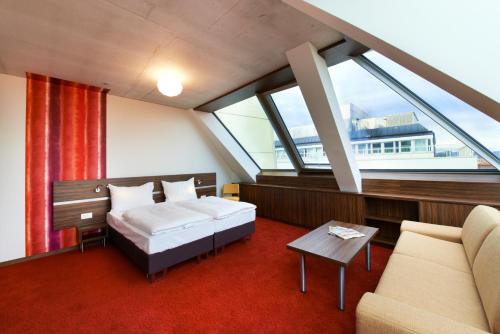 ein Schlafzimmer mit einem Bett und einem Sofa in einem Zimmer in der Unterkunft Simm's Hotel - cityhotel next to Metro U3 in Wien