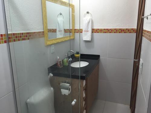 y baño con lavabo, espejo y ducha. en Flat no La Piazzetta - Ap. 14 Térreo, en Pipa