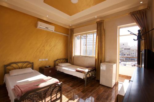 a bedroom with two beds and a large window at Sun Rise Hotel & Hostel & Tours in Amman