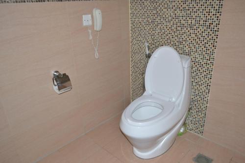 a bathroom with a toilet with a phone on the wall at Tiffany Diamond Hotels Ltd - Indira Gandhi street in Dar es Salaam