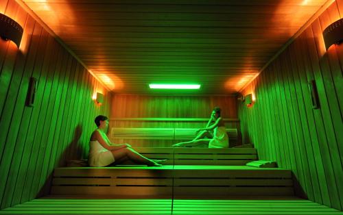 a man and a woman sitting on steps in a room with green lights at Asam Hotel in Straubing