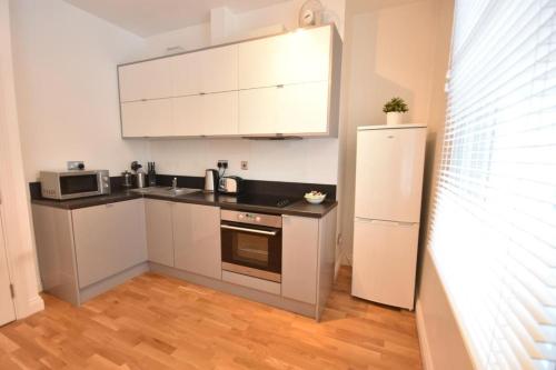  La cuisine est équipée de placards blancs et d'un réfrigérateur. dans l'établissement Apt 2, Soho Apartments 1st floor by Indigo Flats, à Londres