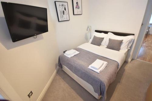 a bedroom with a bed and a flat screen tv at Apt 2, Soho Apartments 1st floor by Indigo Flats in London