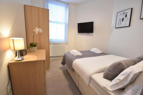 a bedroom with a bed and a table with a lamp at Apt 2, Soho Apartments 1st floor by Indigo Flats in London