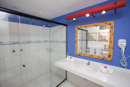 a bathroom with a shower and a sink and a mirror at Porto da Lua Boutique Hotel in Praia do Forte