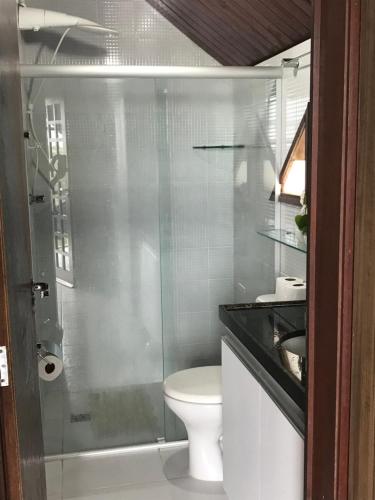 a bathroom with a toilet and a glass shower at Chalé no Condomínio Serra Nevada I in Bananeiras