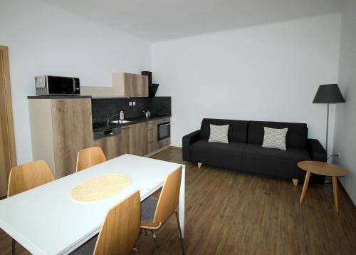 a living room with a white table and a black couch at Apartmány Na sadech Třeboň in Třeboň