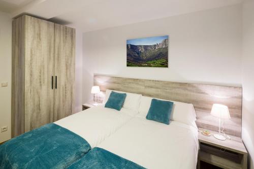 a bedroom with a large white bed with blue pillows at Ciudad de Orduña in Orduña