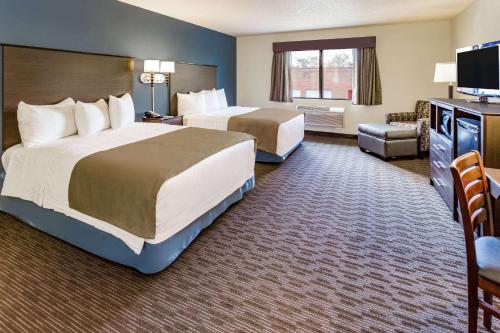 a hotel room with two beds and a television at AmericInn by Wyndham Hotel and Suites Long Lake in Long Lake
