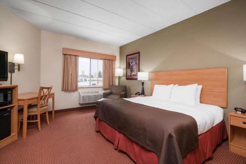 a hotel room with a large bed and a desk at AmericInn by Wyndham Anamosa in Anamosa