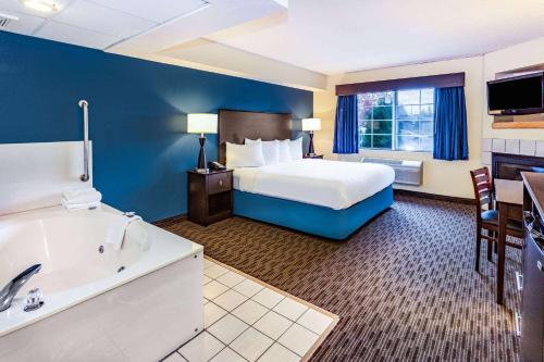 a hotel room with a bed and a bath tub at AmericInn by Wyndham Hotel and Suites Long Lake in Long Lake