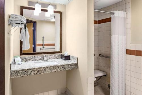 a bathroom with a sink and a mirror and a shower at AmericInn by Wyndham Blue Earth in Blue Earth