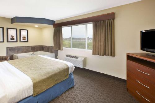 a hotel room with a bed and a flat screen tv at AmericInn by Wyndham Bay City in Bay City