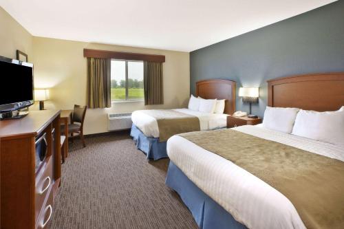 a hotel room with two beds and a flat screen tv at AmericInn by Wyndham Bay City in Bay City