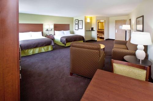 a hotel room with two beds and a couch and chairs at AmericInn by Wyndham Osage in Osage