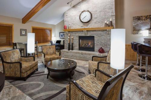 a living room with a fireplace and a table and chairs at AmericInn by Wyndham Sartell in Sartell