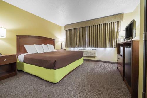 a hotel room with a bed and a flat screen tv at AmericInn by Wyndham Sioux Falls in Sioux Falls
