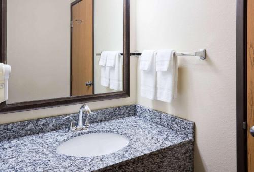 y baño con lavabo, espejo y toallas. en AmericInn by Wyndham Sartell, en Sartell