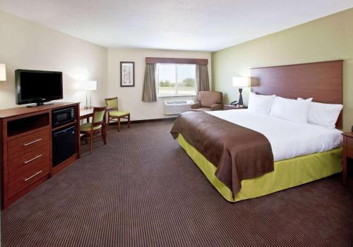 a hotel room with a bed and a flat screen tv at AmericInn by Wyndham Osage in Osage