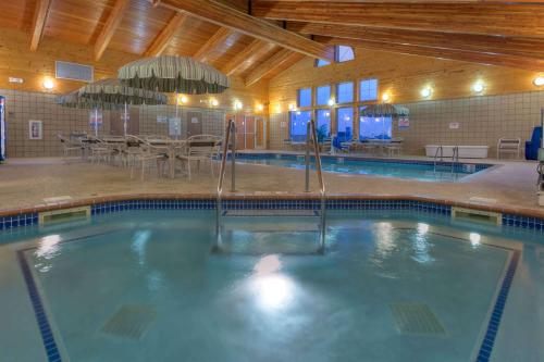 a swimming pool with tables and chairs in a building at AmericInn by Wyndham Newton in Newton