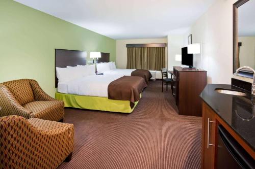 um quarto de hotel com uma cama grande e uma cadeira em AmericInn by Wyndham DeWitt em De Witt