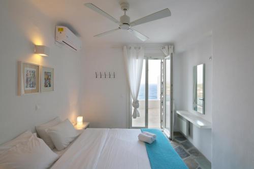 1 dormitorio blanco con 1 cama y ventilador de techo en Plan-B Holidays, en Playa Kalo Livadi