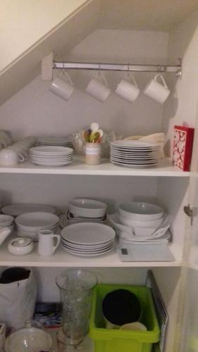 a shelf filled with plates and cups and dishes at Das Rosenhaus in Utersum