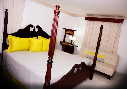 ein Schlafzimmer mit einem großen Bett mit gelben Kissen in der Unterkunft Hotel Los Jardines in Santiago de los Caballeros