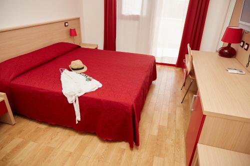 a bedroom with a red bed with a hat on it at Hotel Residence Key Club in Montalto di Castro