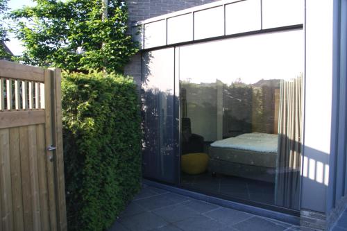 une extension en verre d'une maison avec un lit à l'intérieur dans l'établissement La Chambre d'Amis, à Ypres