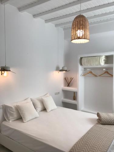 a white bedroom with a large white bed with two pillows at Mykonos Unique Apartment in Mikonos