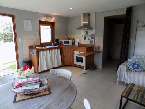 eine Küche und ein Wohnzimmer mit einem Tisch, einer Küche und einem Zimmer in der Unterkunft Gite des pâtissons in La Foret Du Parc