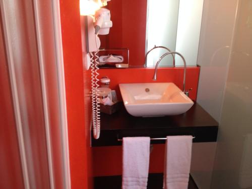 a bathroom with a sink and a mirror and towels at Boutique Hotel La Rinascente in Locarno
