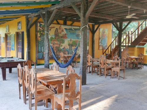 um restaurante com mesas e cadeiras de madeira e uma rede de descanso em El Peregrino em Moyogalpa