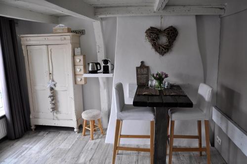 a dining room with a wooden table and white chairs at De Slapende Leeuw in Middelburg