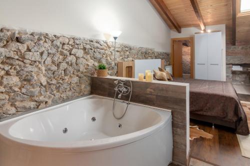 a bath tub in a bathroom with a stone wall at Estudio Sonido y Jacuzzi in Santander