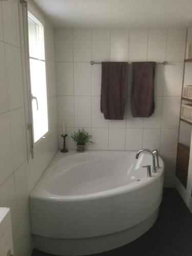 baño con bañera blanca y ventana en Lakeviewhouse en Sundlauenen